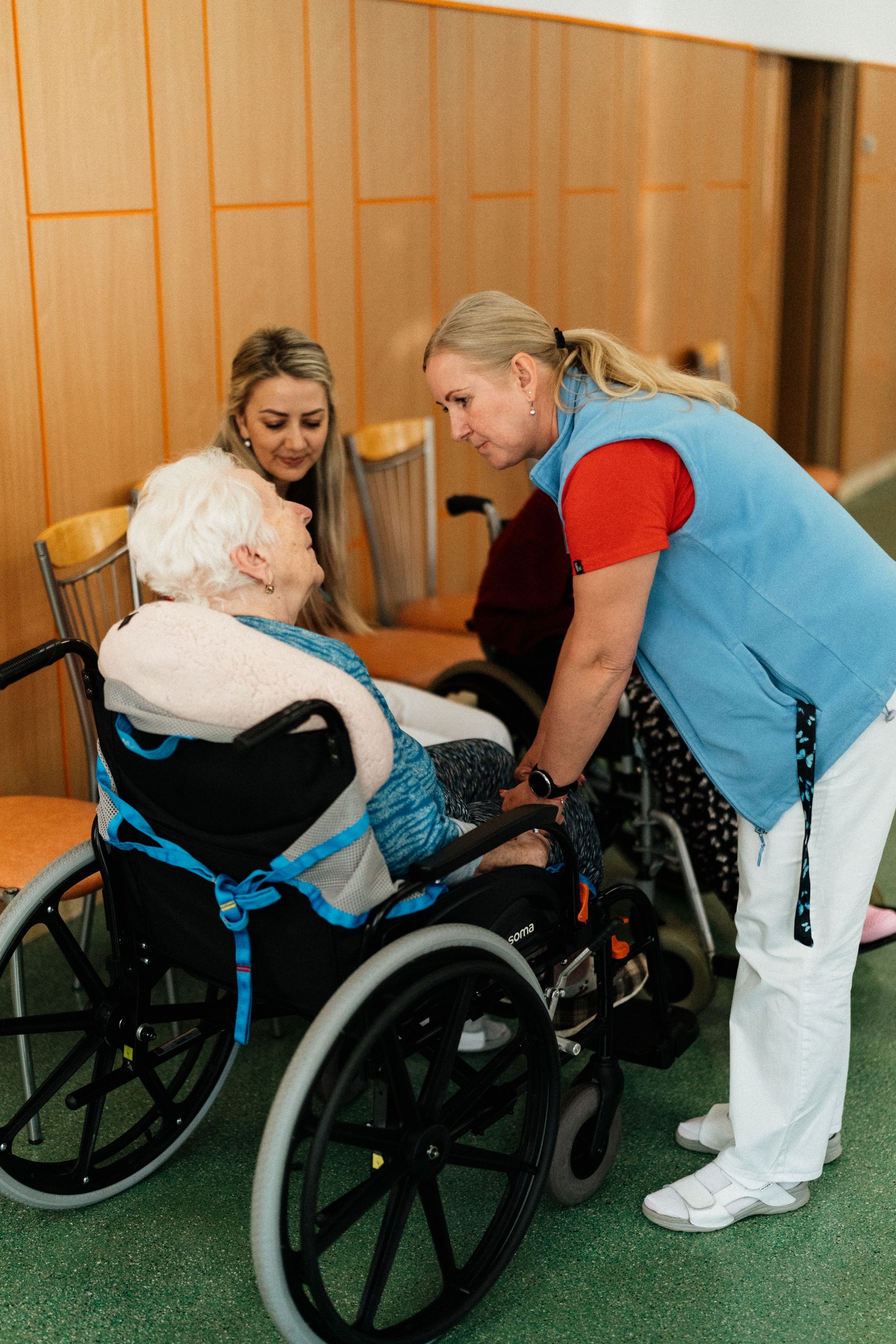 A caregiver kneels to talk face to face with a resident in a wheelchair