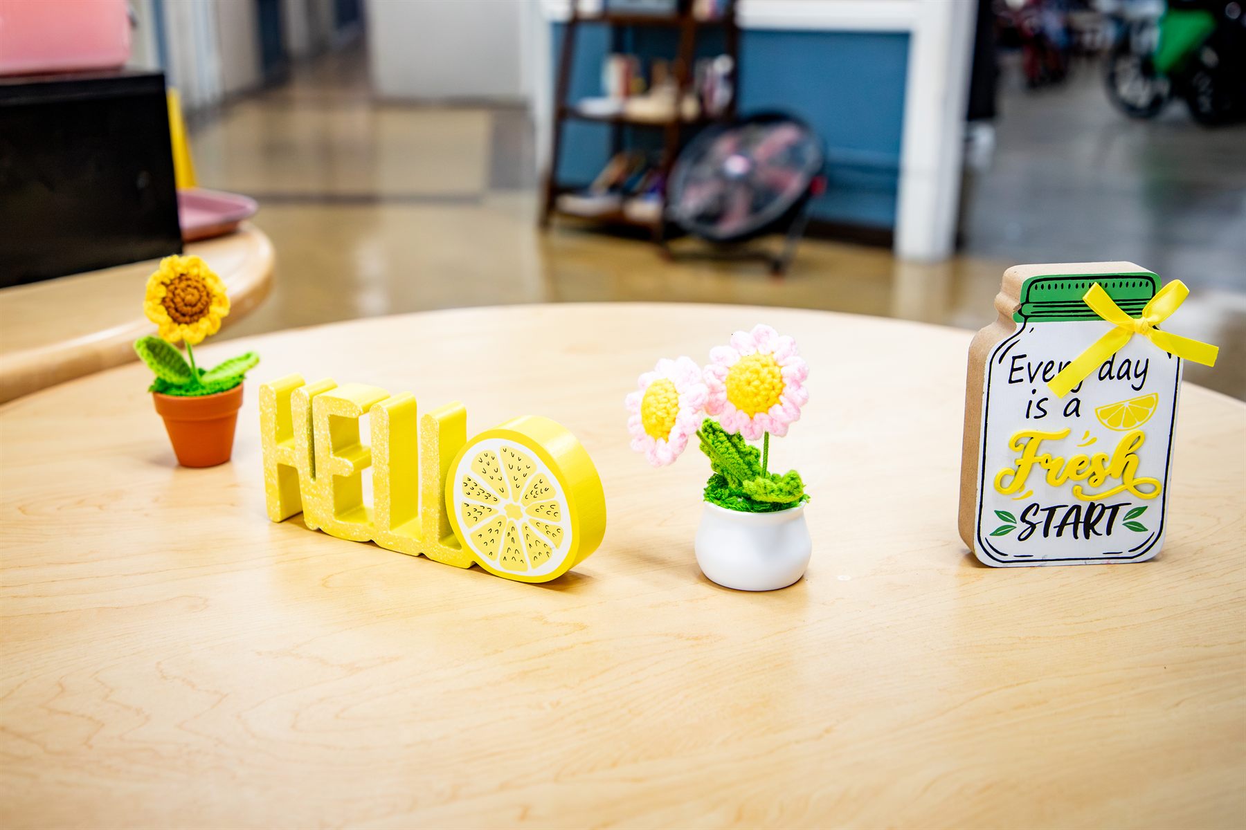 A cheerful welcome table with a yellow HELLO sign and crocheted flowers