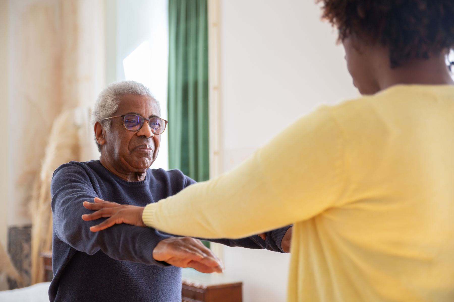A therapist guides a resident through an arm-strengthening exercise