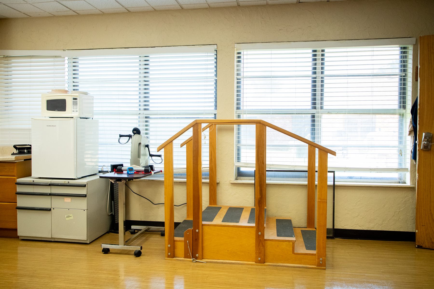Windsor Hills therapy gym with practice stairs, a pedal exerciser and bright windows